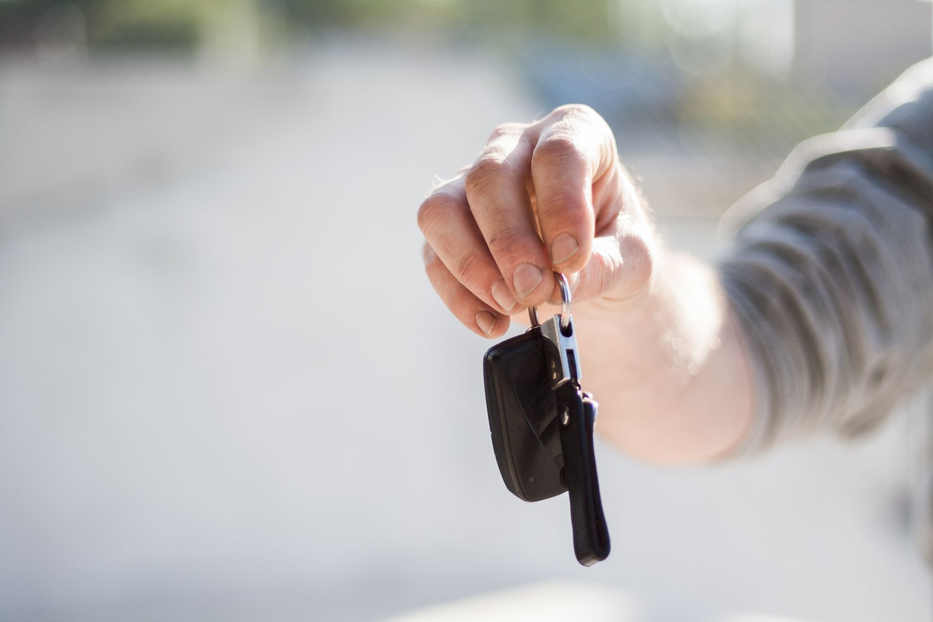 A hand holding out a set of car keys, the moment a learner permit turns into actual driving