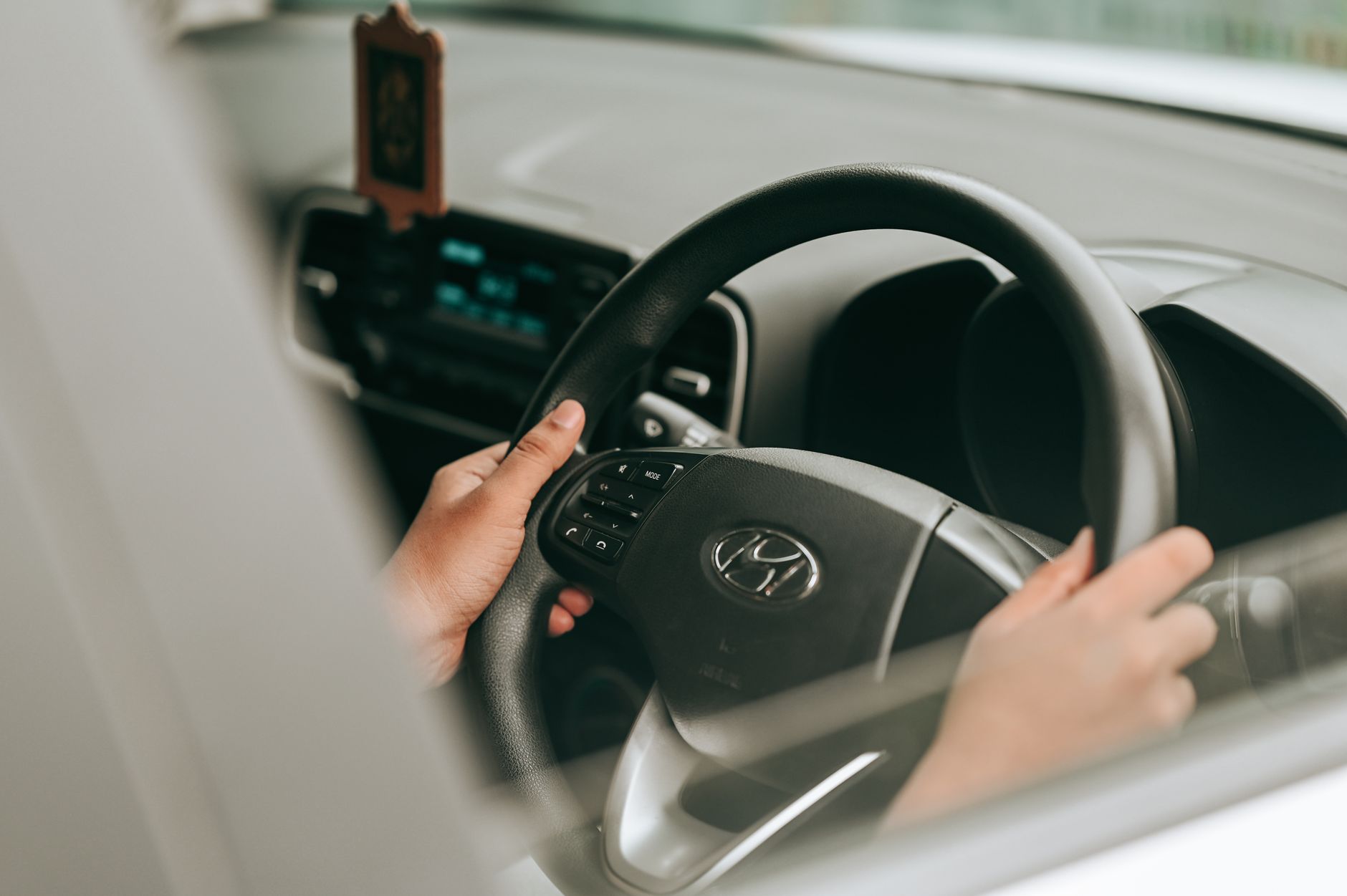 A pair of hands resting easy on a car steering wheel, the settled grip of someone who has driven this city for a living