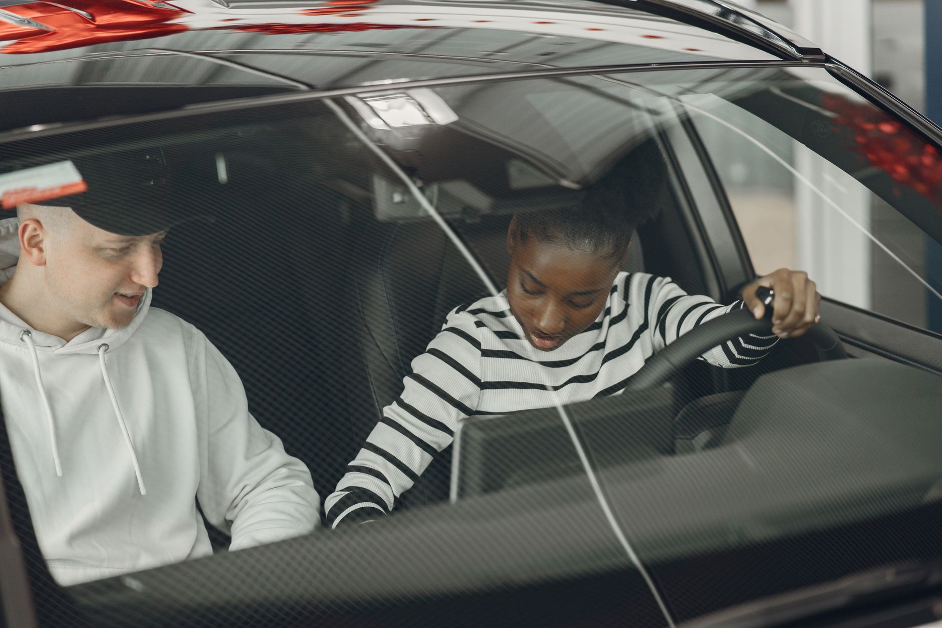 An instructor and a learner talking something through in a parked car during a driving lesson