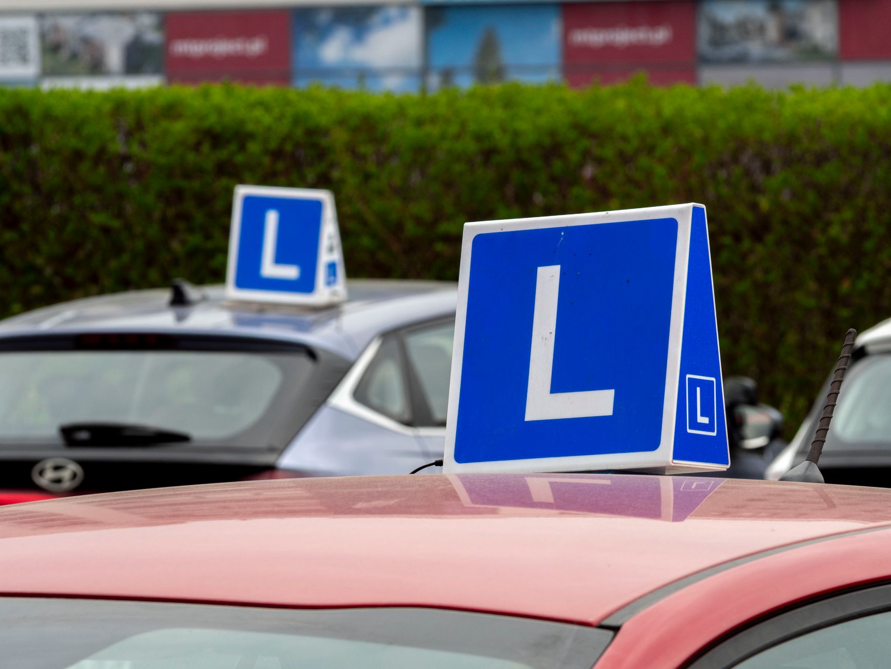 Driving-school cars with learner signs parked in a training area, the kind used for test preparation