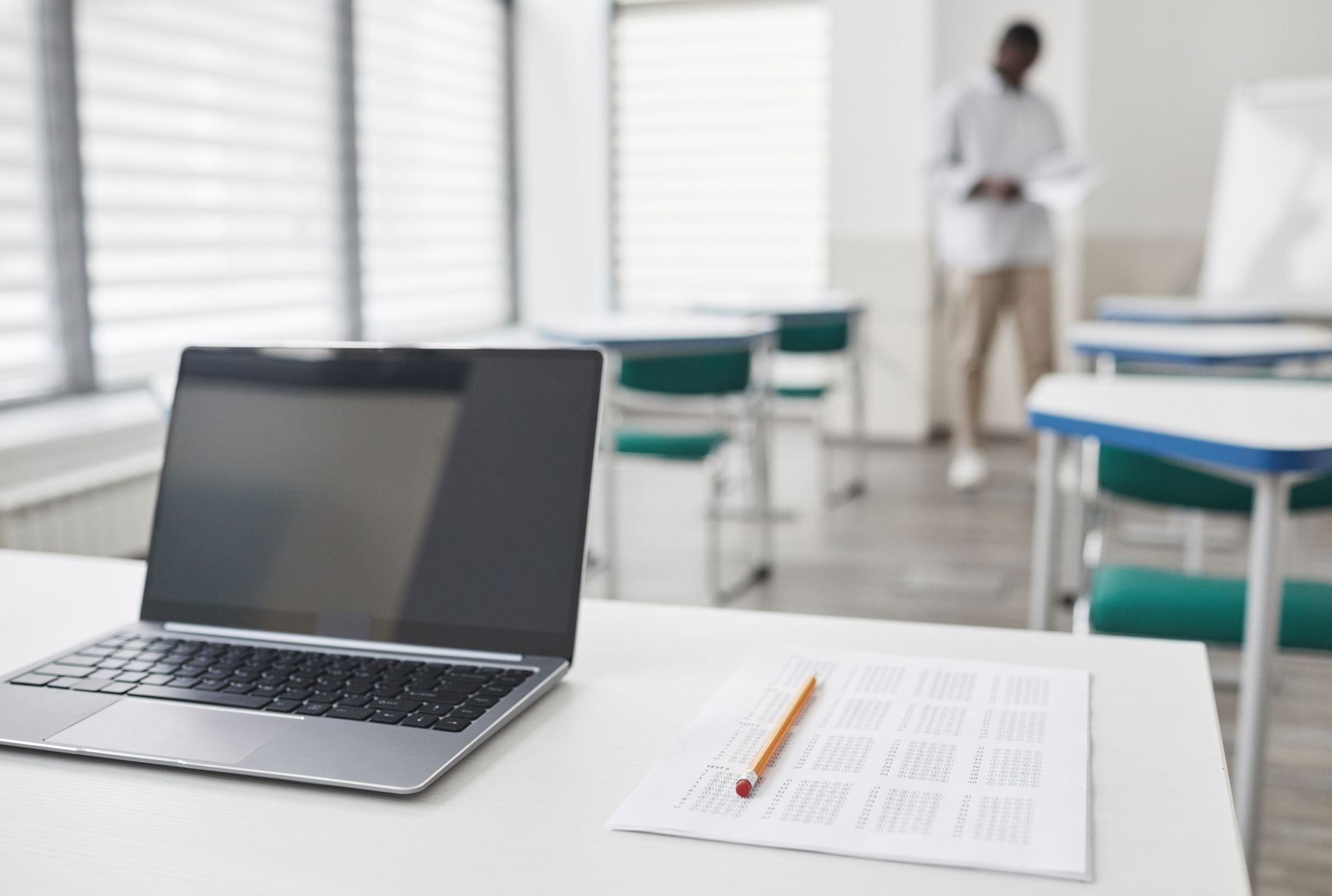 A laptop and an exam sheet on a desk, the setup of someone preparing for a written test
